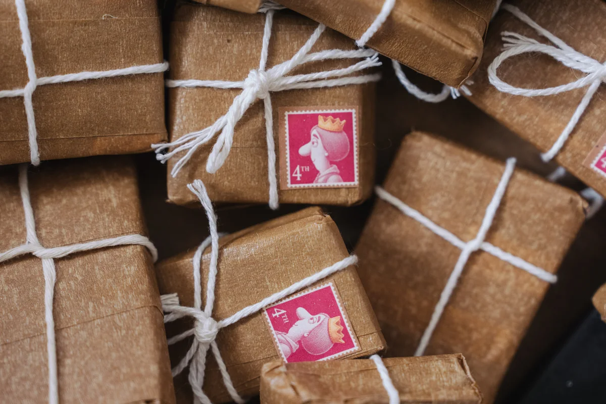 Handmade brown-paper parcels tied with string and finished with pink character stamps, made for the audience delivery game.
